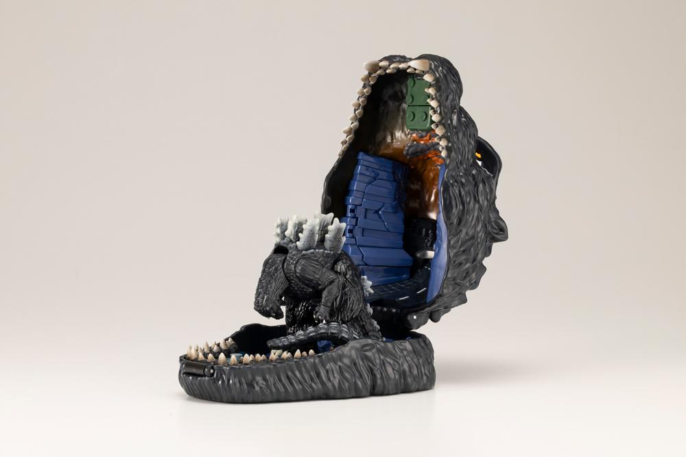 Opened Godzilla pocket playset revealing city backdrop and Godzilla figure from behind.