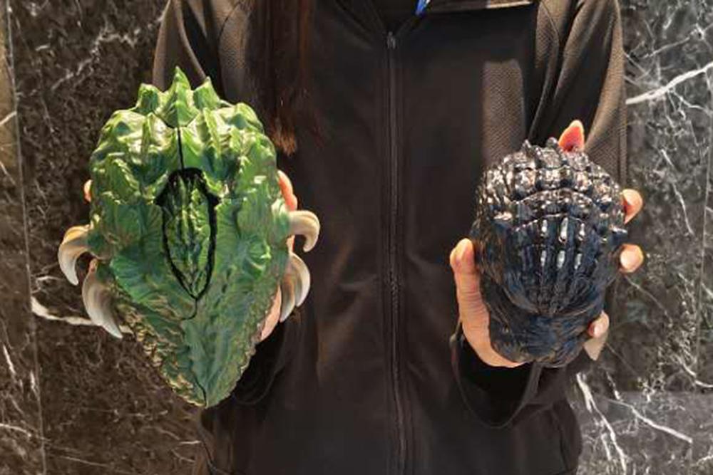 Closed Biollante and Godzilla pocket toys held in hands to illustrate product scale.