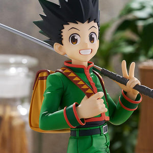 Medium close-up portrait of the cheerful Gon Freecss figure under warm ambient lighting against an antique library diorama background.