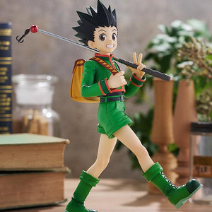Full-body display of the L size Gon Freecss figure positioned within a warm, rustic study diorama backdrop alongside vintage books and ambient plants.