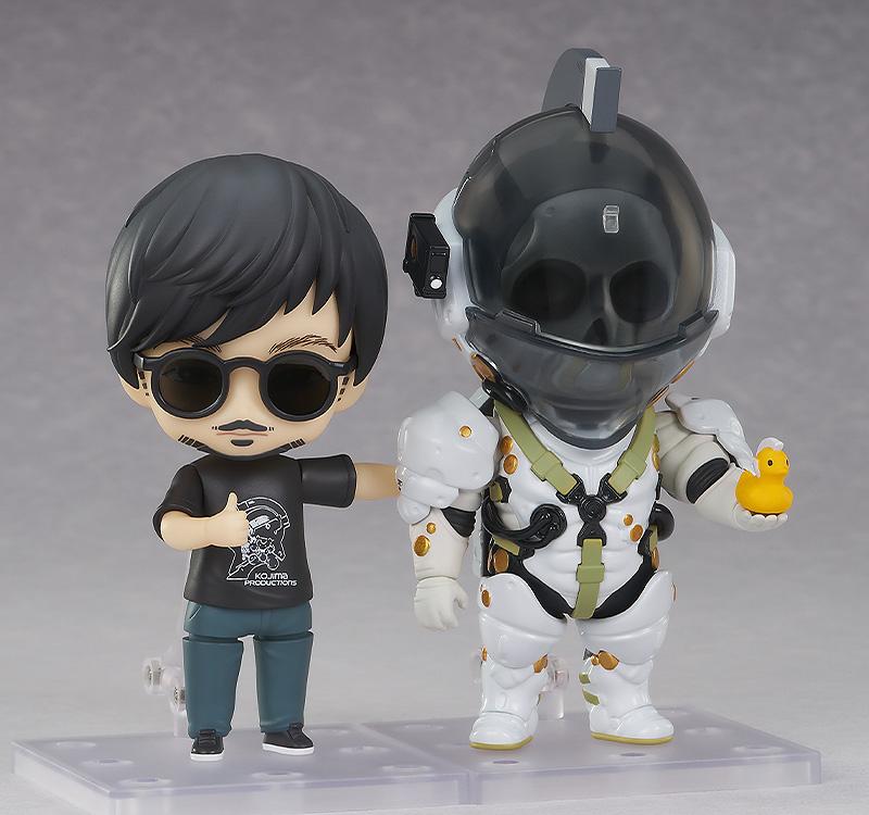 Hideo Kojima Nendoroid in sunglasses posed side-by-side with Nendoroid Ludens figure holding a mini yellow duck.