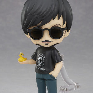 Hideo Kojima Nendoroid figure equipped with dark round sunglasses holding the yellow Ludens Duck accessory in palm.