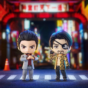 Kiryu and Majima Nendoroid figures standing side-by-side on a crosswalk, set in a dynamic nighttime city street diorama.