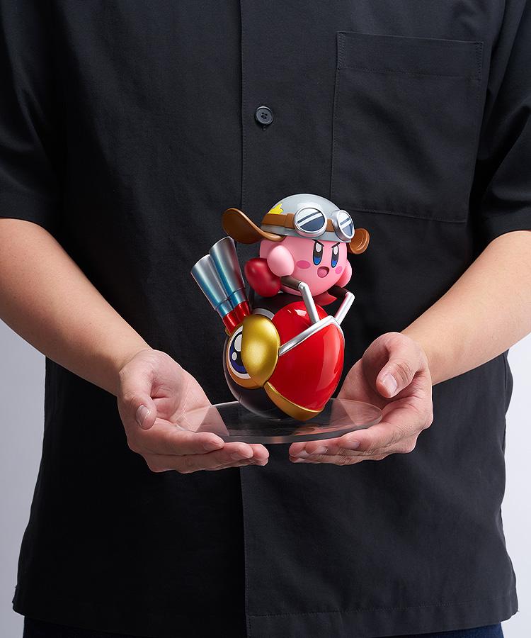 A person holding the 5.51-inch tall Pop Up Parade Kirby Wheelie Rider figure on its clear base, providing a real-world size and scale reference.
