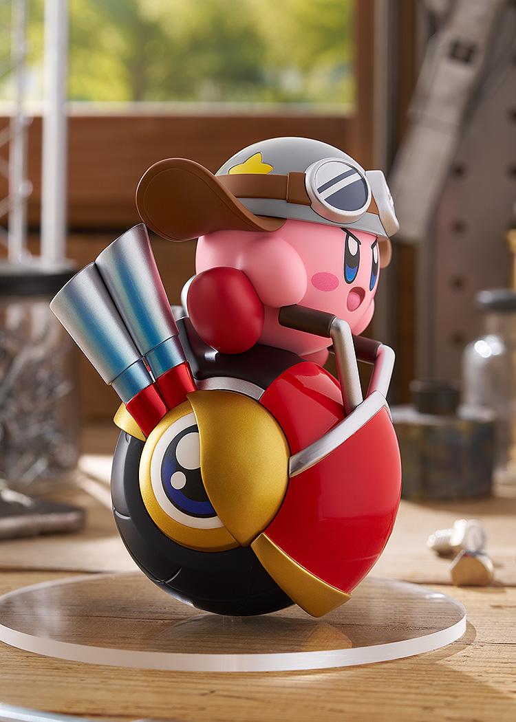 Right profile view of the Kirby Wheelie Rider figure in a workshop environment, highlighting the curved red body and gold side accents of the Wheelie vehicle.