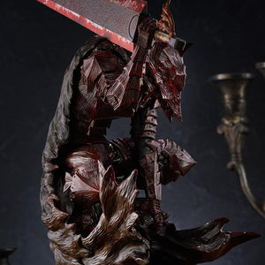 Close-up of Guts crouched in armor with blood painted plates and grip on Dragon Slayer sword hilt