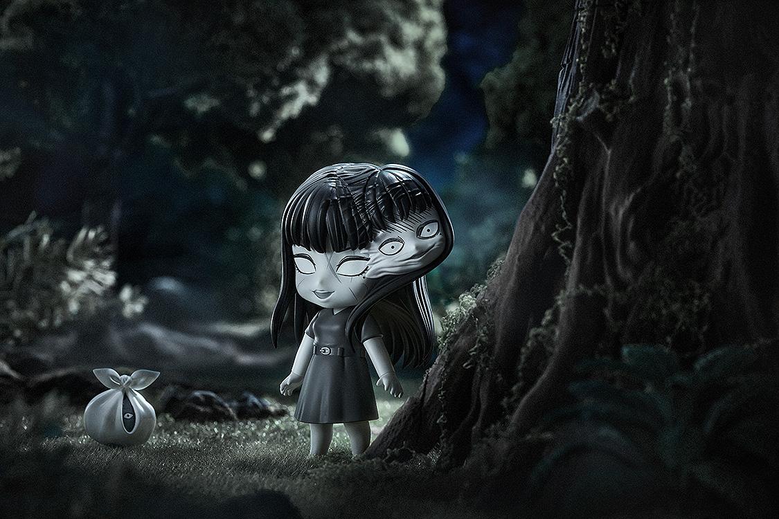 Atmospheric night scene of Tomie Nendoroid with multiple faces next to a large tree and mysterious bag.