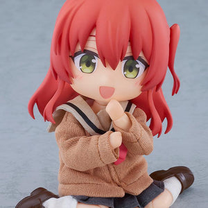 Cute floor-sitting pose of the highly articulated Ikuyo Kita Nendoroid Doll figure resting with her hands near her face and a happy expression.