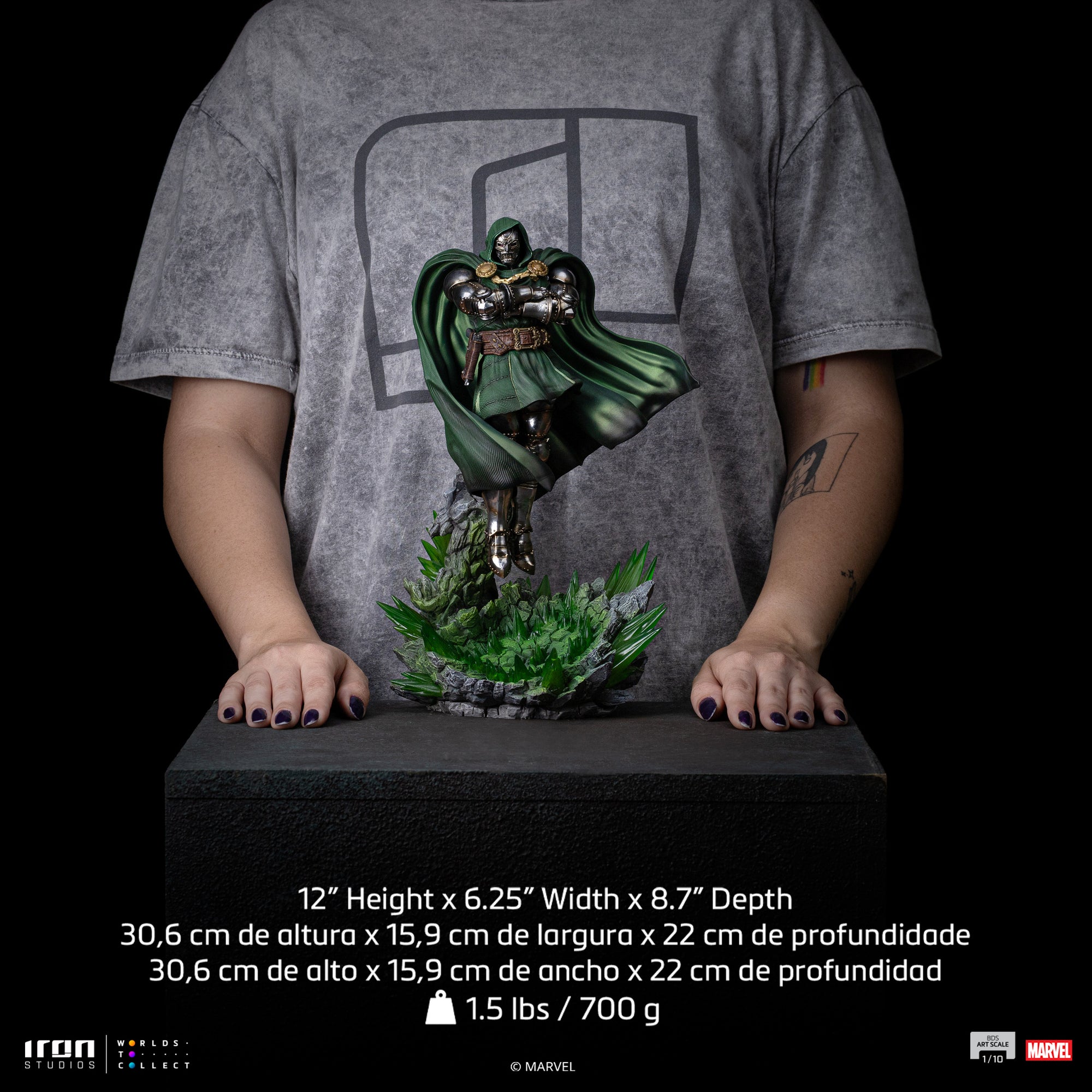 A size comparison photo of the Iron Studios Doctor Doom statue held by hands, with its height of 12", width of 6.25" and depth of 8.7" listed for scale.