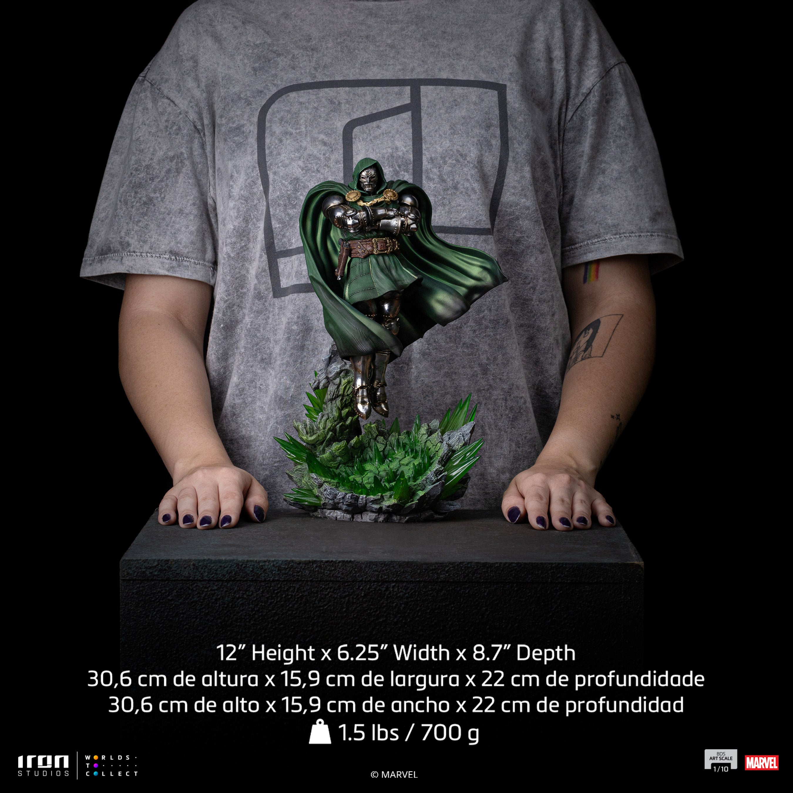 A size comparison photo of the Iron Studios Doctor Doom statue held by hands, with its height of 12", width of 6.25" and depth of 8.7" listed for scale.