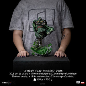 A size comparison photo of the Iron Studios Doctor Doom statue held by hands, with its height of 12", width of 6.25" and depth of 8.7" listed for scale.