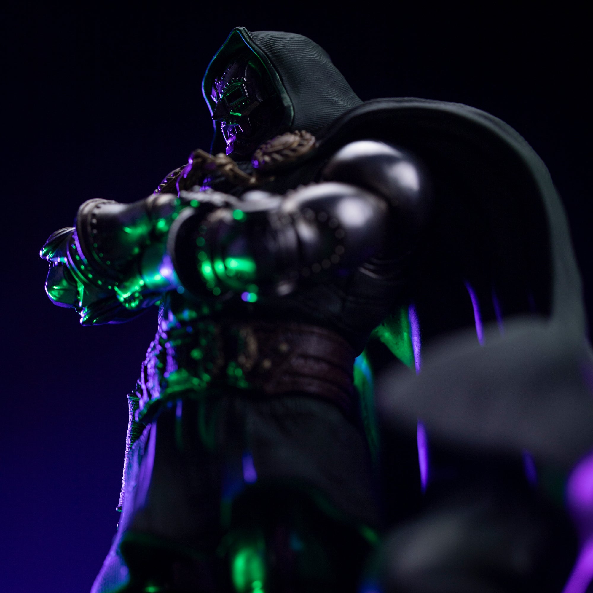A mid-range close-up of the Doctor Doom statue, focusing on the dark shadows cast by his hood and the detail of his armored gauntlets.