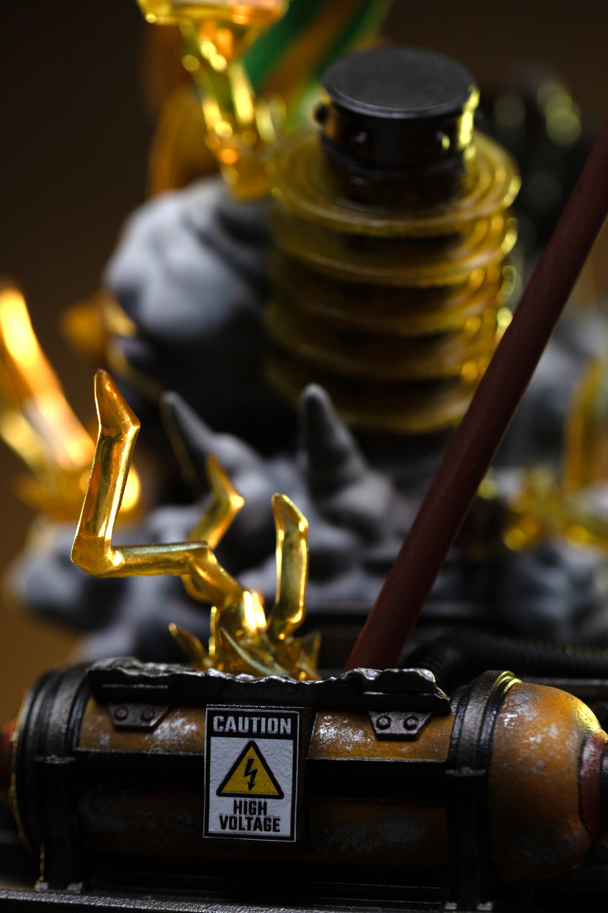 A close-up of the industrial diorama base, showing a caution sign reading "HIGH VOLTAGE" next to a glowing lightning effect.