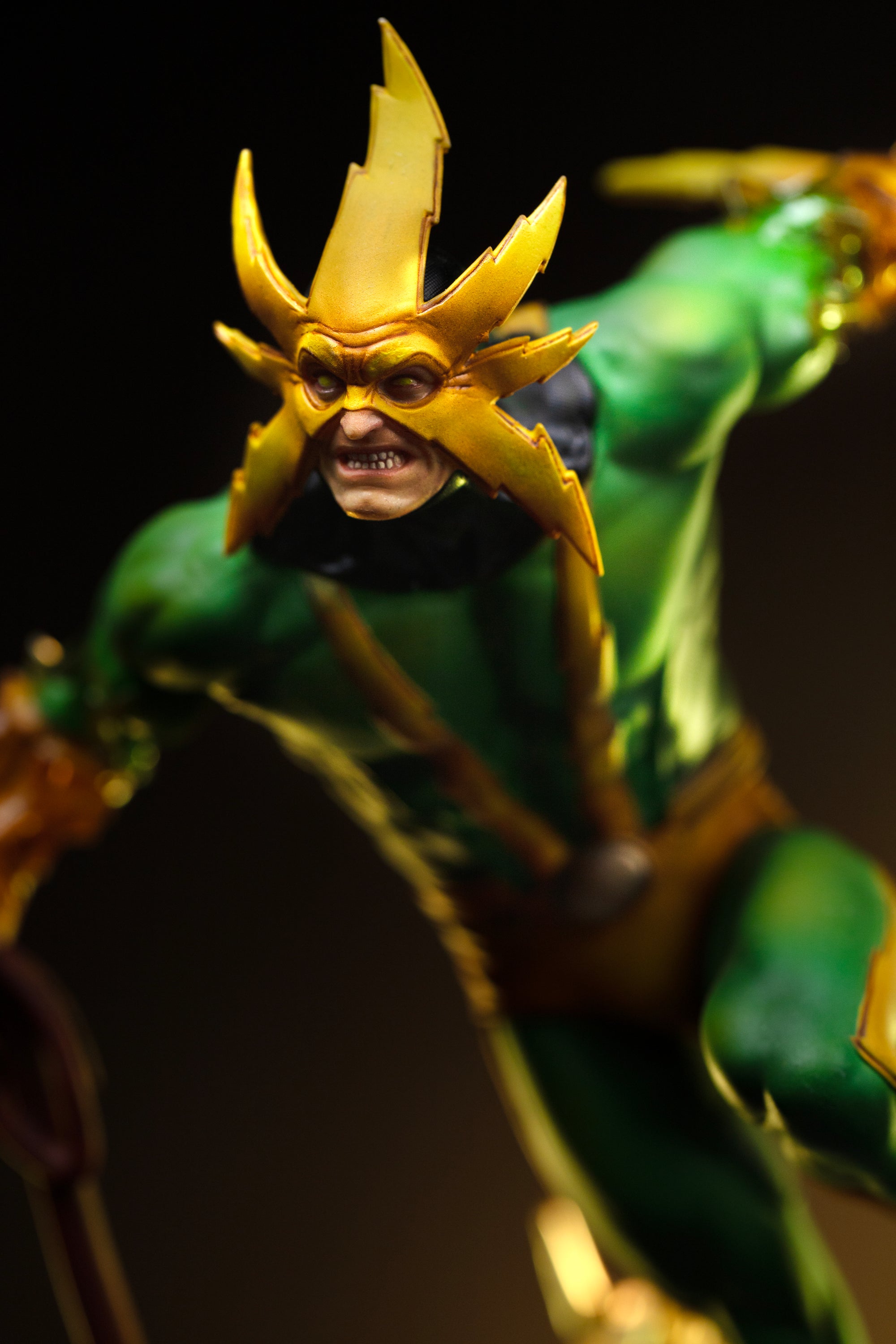 A close-up of the Electro statue's upper body, highlighting the detail on his mask and the texture of his green and yellow suit.