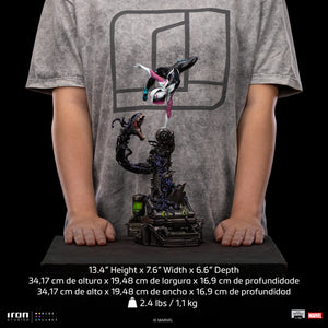 A size comparison photo of the Iron Studios Ghost-Spider 1/10 Scale Statue held by hands, with its 13.4-inch height, 7.6-inch width and 6.6" depth dimensions listed.