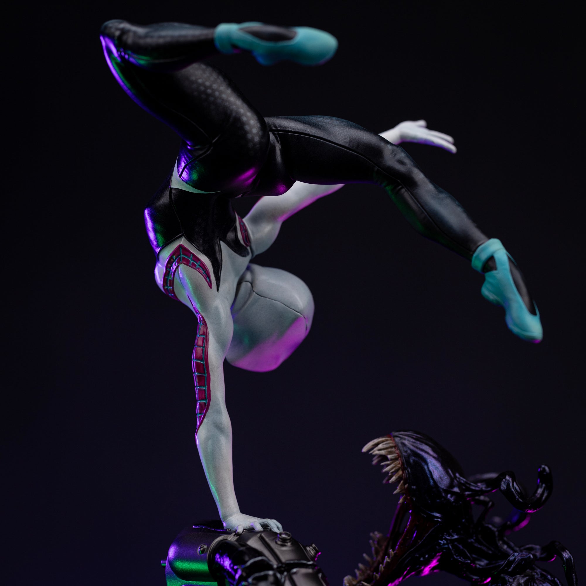 A close-up of Ghost-Spider's torso and legs, highlighting the sculpted texture of her suit as she balances on one hand above the base.