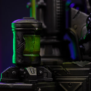 A detailed close-up of the Ghost-Spider diorama base, showing a cracked industrial canister with glowing green liquid inside.