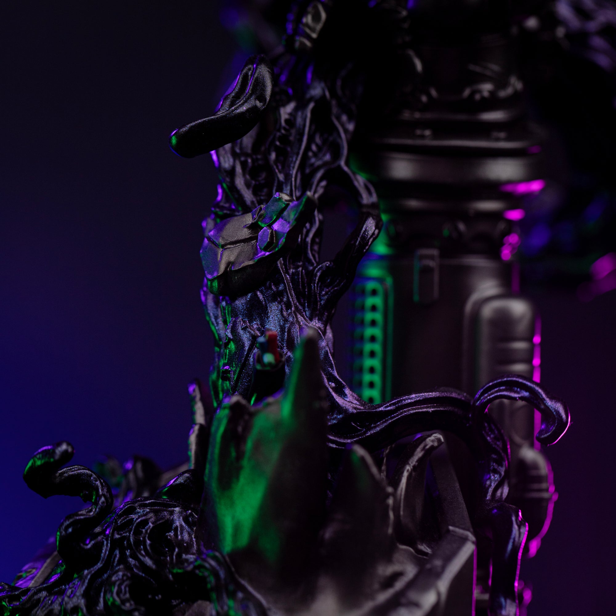 A close-up of the base, focusing on the dark, twisting symbiote tendrils wrapping around the industrial metal parts.