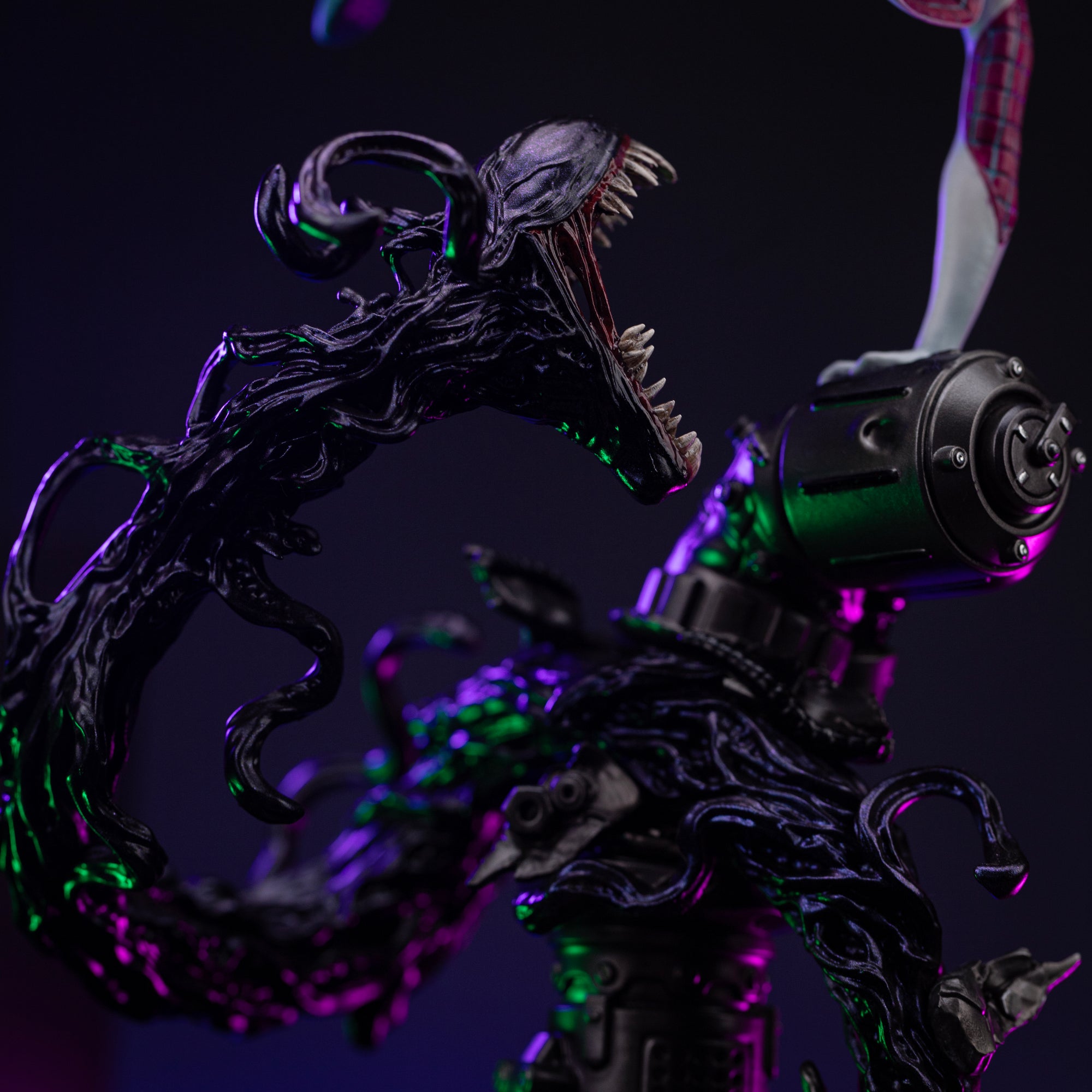 Close-up detail of the symbiotic tendril on the base, showing its menacing open mouth, sharp teeth, and black, glossy texture.