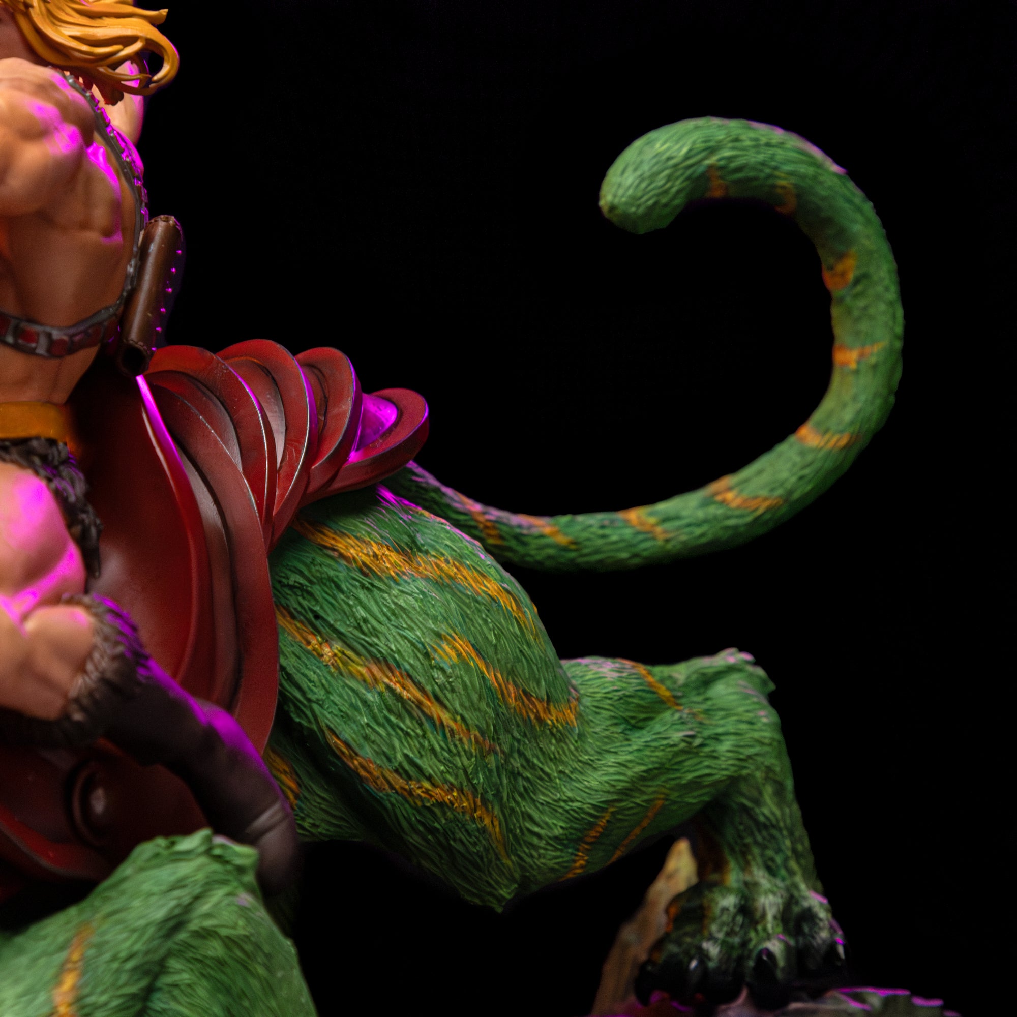 Close-up of the back of the Iron Studios Battle Cat statue, detailing his curled green and yellow tail and the back of his dark red saddle.