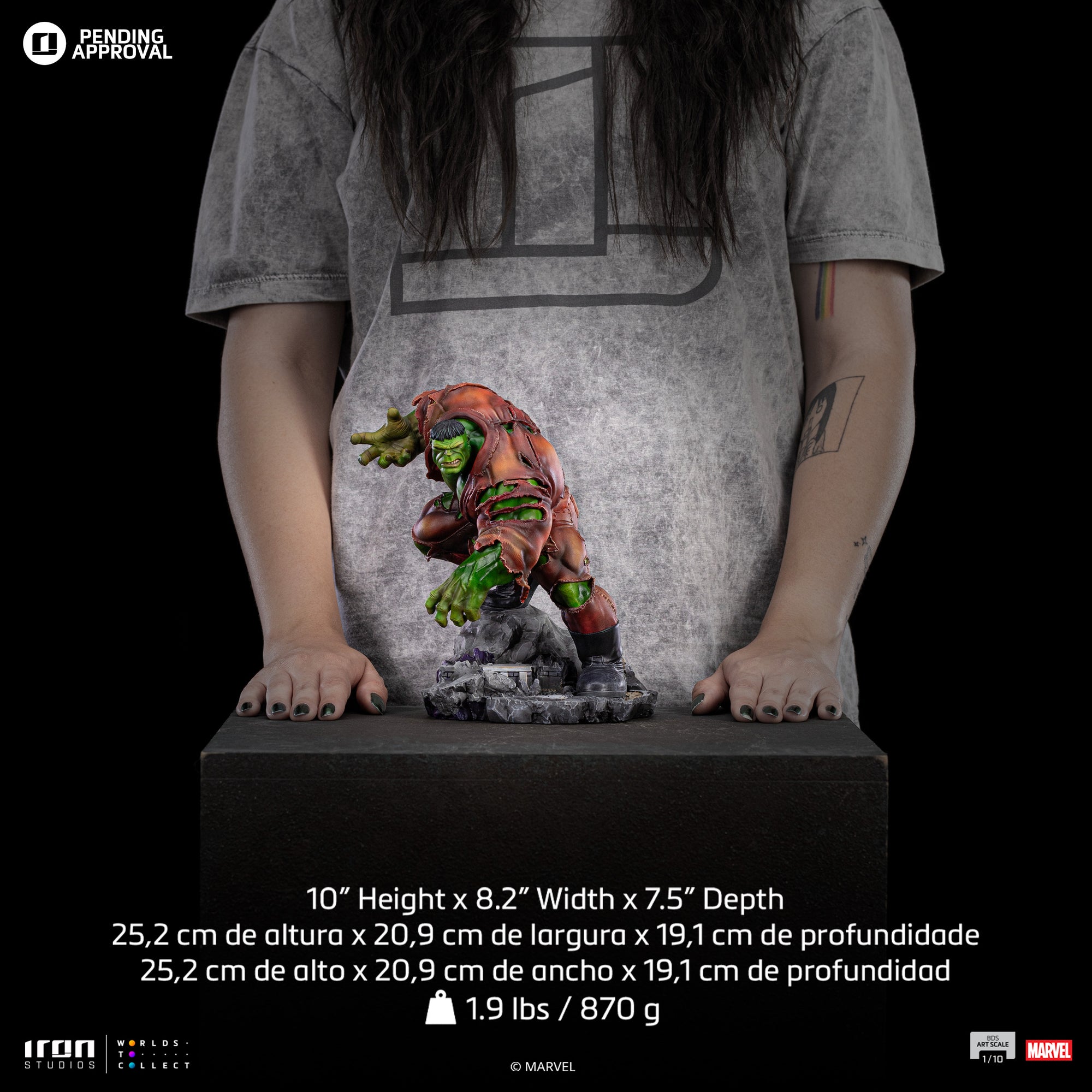 A size comparison photo of the Iron Studios Hulk 1/10 Scale Statue in front of a person, their hands by its side, with its 10-inch height, 8.2-inches width and 7.5-inches depth.