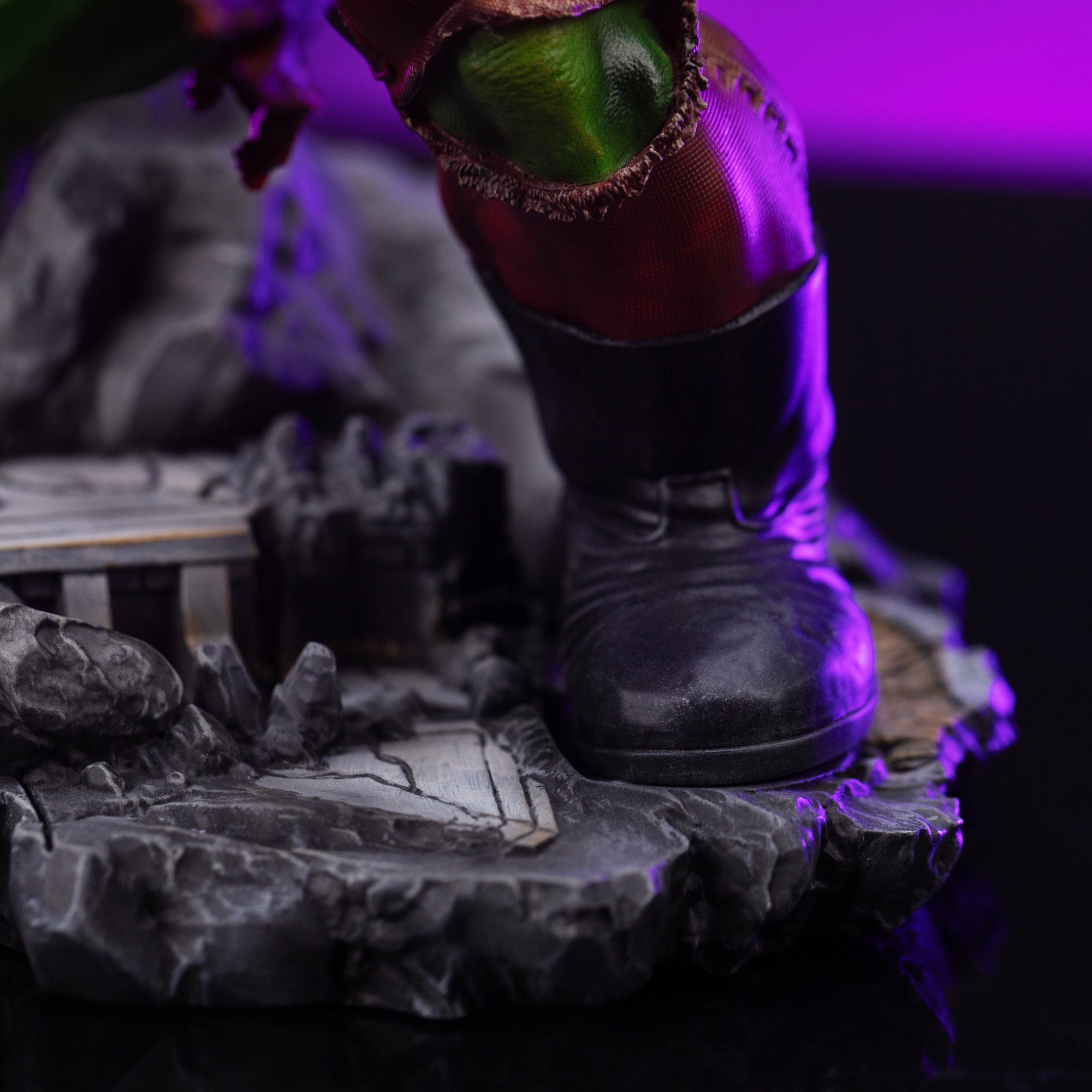 Close-up of Hulk's black boot and lower leg, resting on the detailed, cracked stone diorama base.