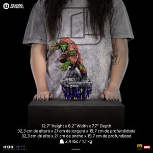 A size comparison photo of the Iron Studios Hulk Deluxe 1/10 Scale Statue standing in front of a person with their hands resting by the side of the statue, with its dimensions listed as 12.7-inch height, 8.2" width, and 7.7" depth.