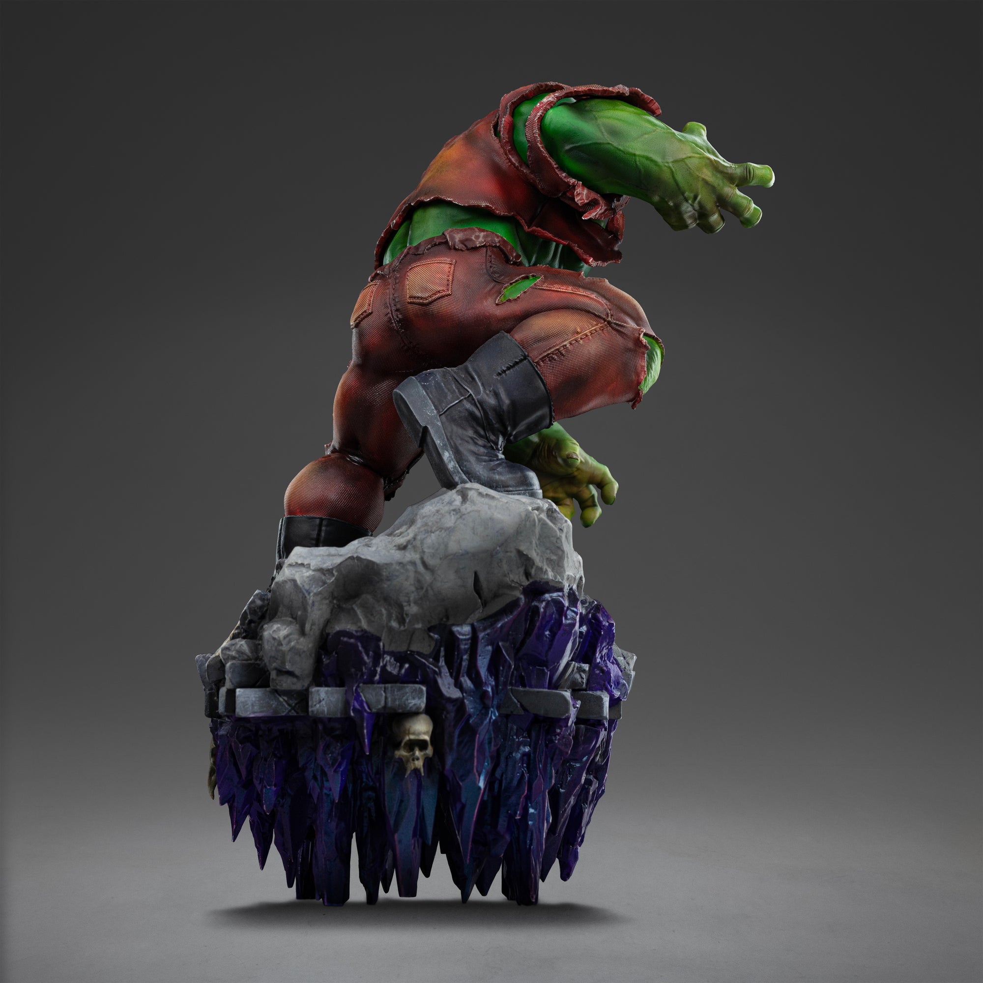 Rear view of the Hulk Deluxe statue, showcasing the texture of his torn clothing and the purple crystal formations extending beneath the base.