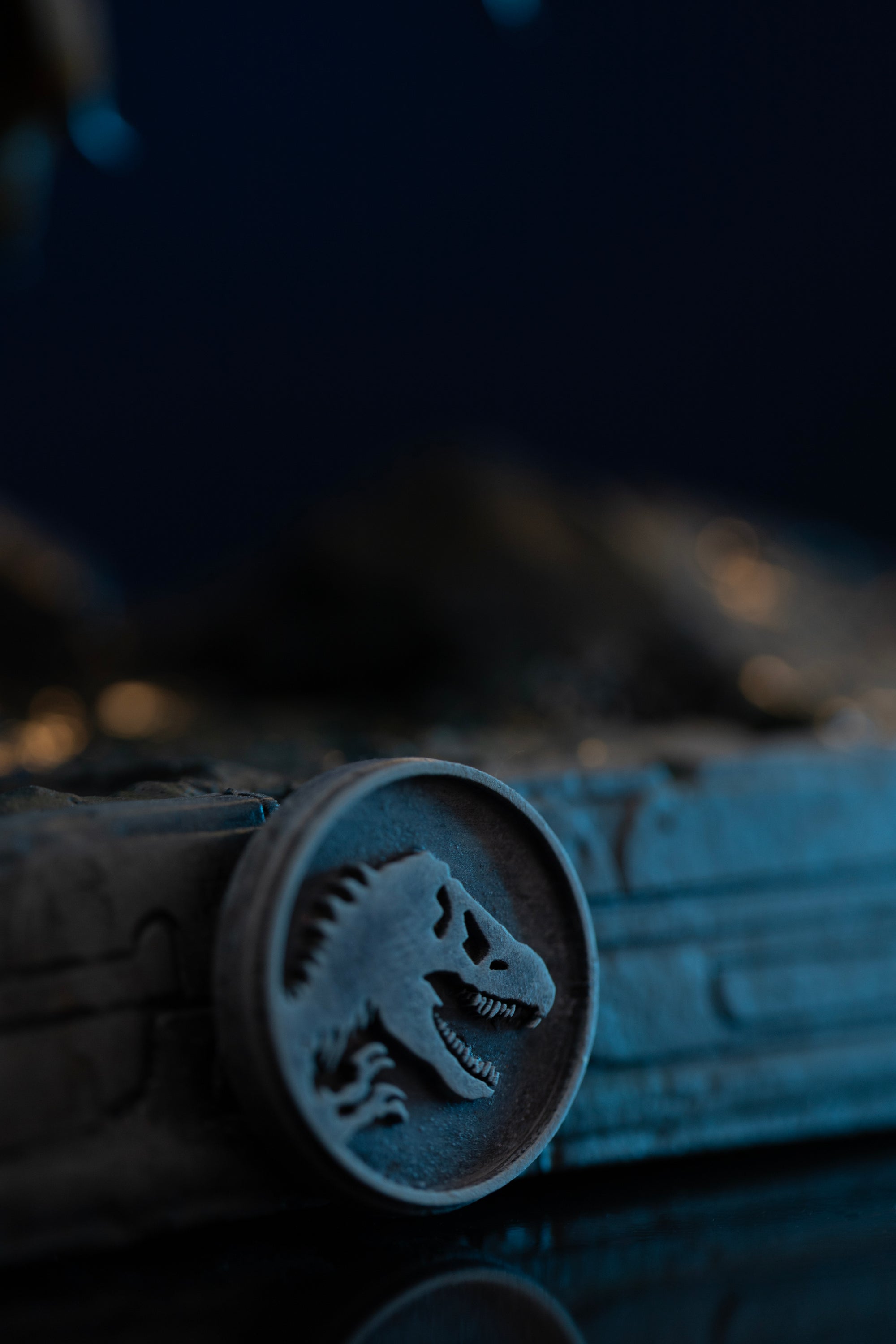Close-up of silver Jurassic World logo medallion on front of Iron Studios Spinosaurus display base