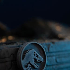 Close-up of silver Jurassic World logo medallion on front of Iron Studios Spinosaurus display base