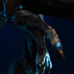 Macro detail of Iron Studios Spinosaurus statue webbed clawed feet and skin texture under blue light