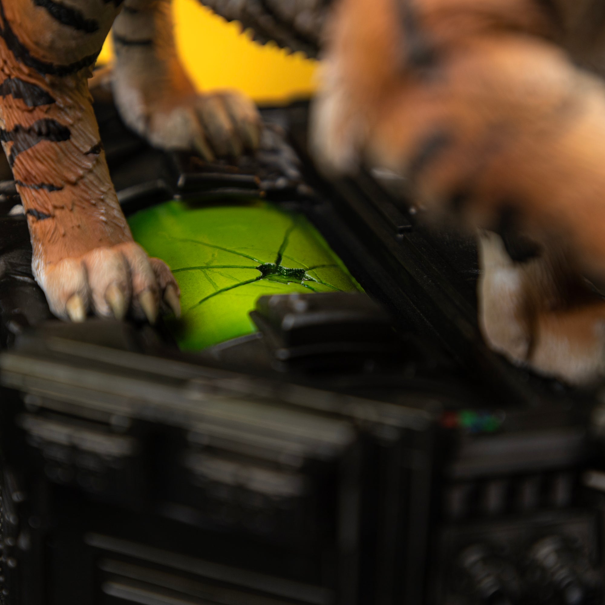 An extreme close-up of the diorama base, showing a tiger paw resting near a glowing, cracked green tech panel.