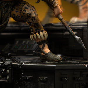 A close-up of Kraven the Hunter's lower leg and foot, highlighting his leopard-print pants, bone anklet, and the tip of his spear weapon.