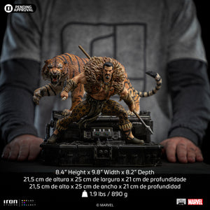A size comparison photo of the Iron Studios Kraven the Hunter statue held by hands, with its height of 8.4", width of 9.8" and depth of 8.2" listed.
