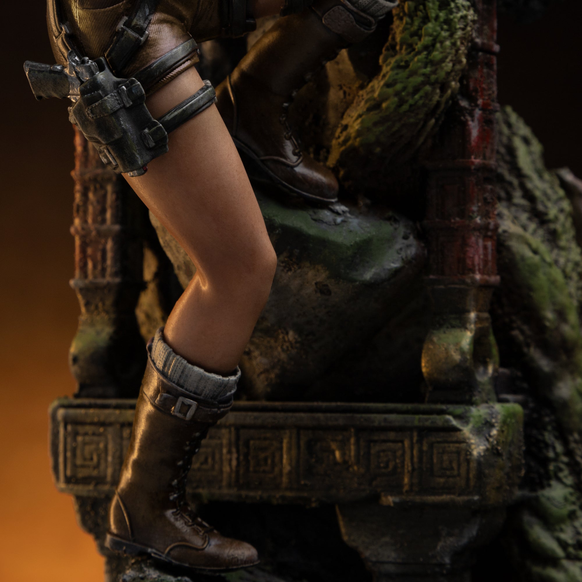 A close-up of Lara Croft's legs on the statue, showing her brown climbing boots and the detailed straps of her thigh holster.