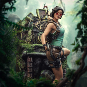 A close-up adventure shot of the Lara Croft statue with sunglasses, pistol, and her green top, set in a lush jungle environment.