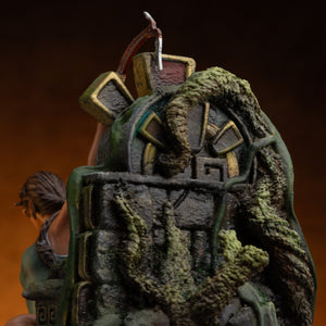 A close-up of the top portion of the ruined totem base from the Lara Croft statue, showing ancient symbols and overgrowth.