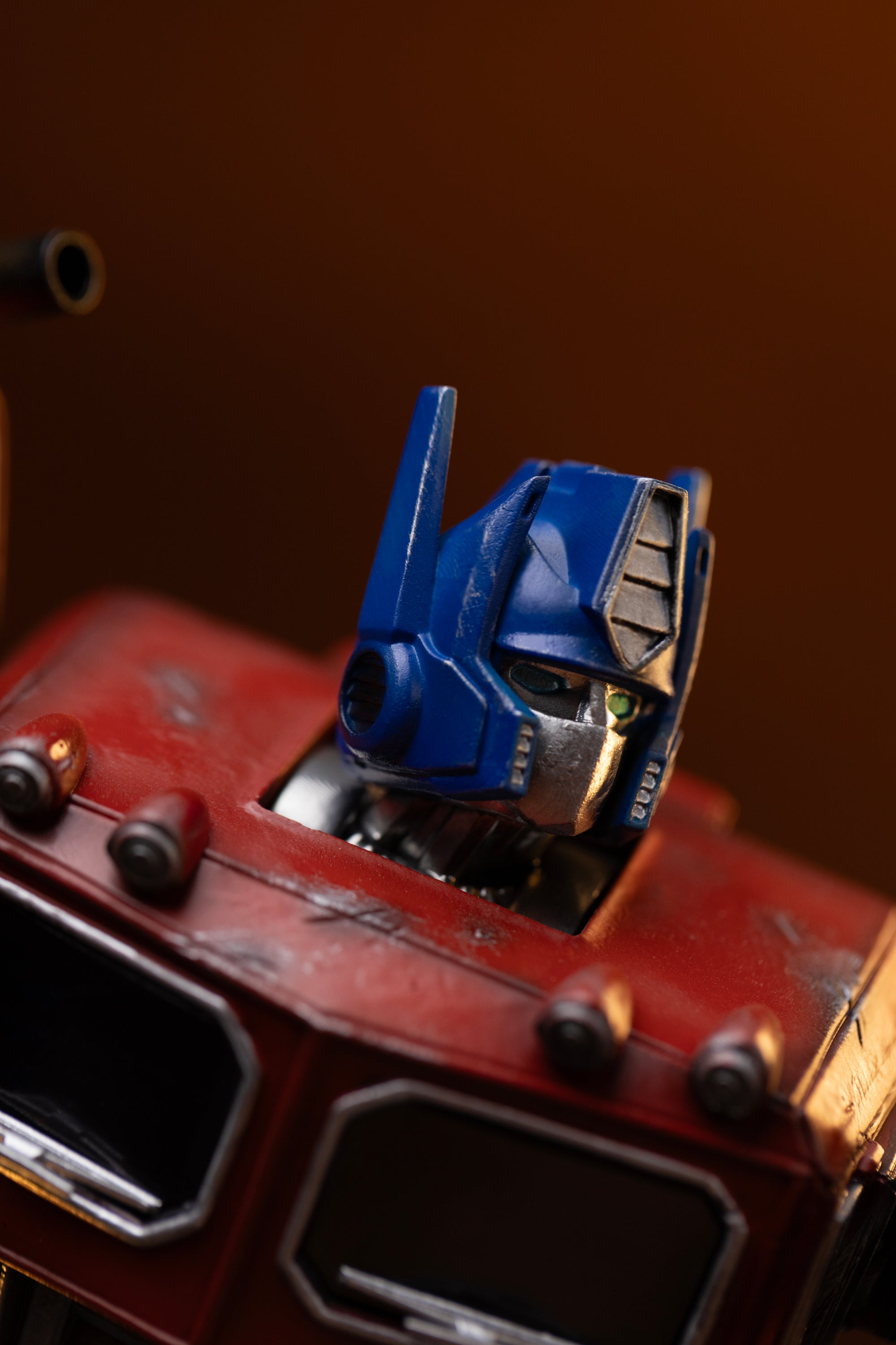 Extreme close-up of Optimus Prime's blue helmet crest, silver faceplate, and green optic eyes on the Iron Studios statue.