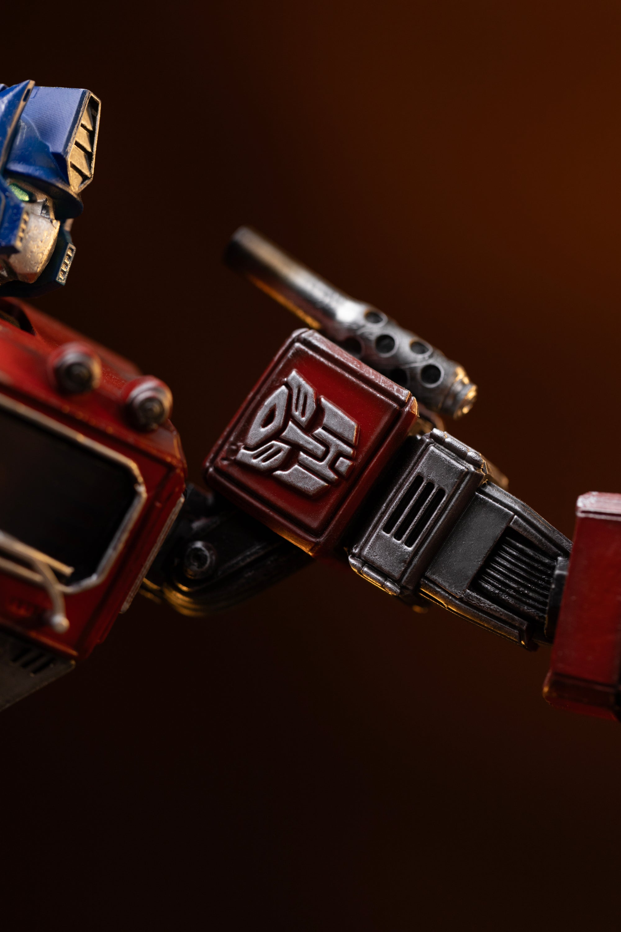 Macro shot of the silver Autobot emblem sculpted on the red shoulder armor of the Iron Studios Optimus Prime statue.