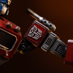 Macro shot of the silver Autobot emblem sculpted on the red shoulder armor of the Iron Studios Optimus Prime statue.