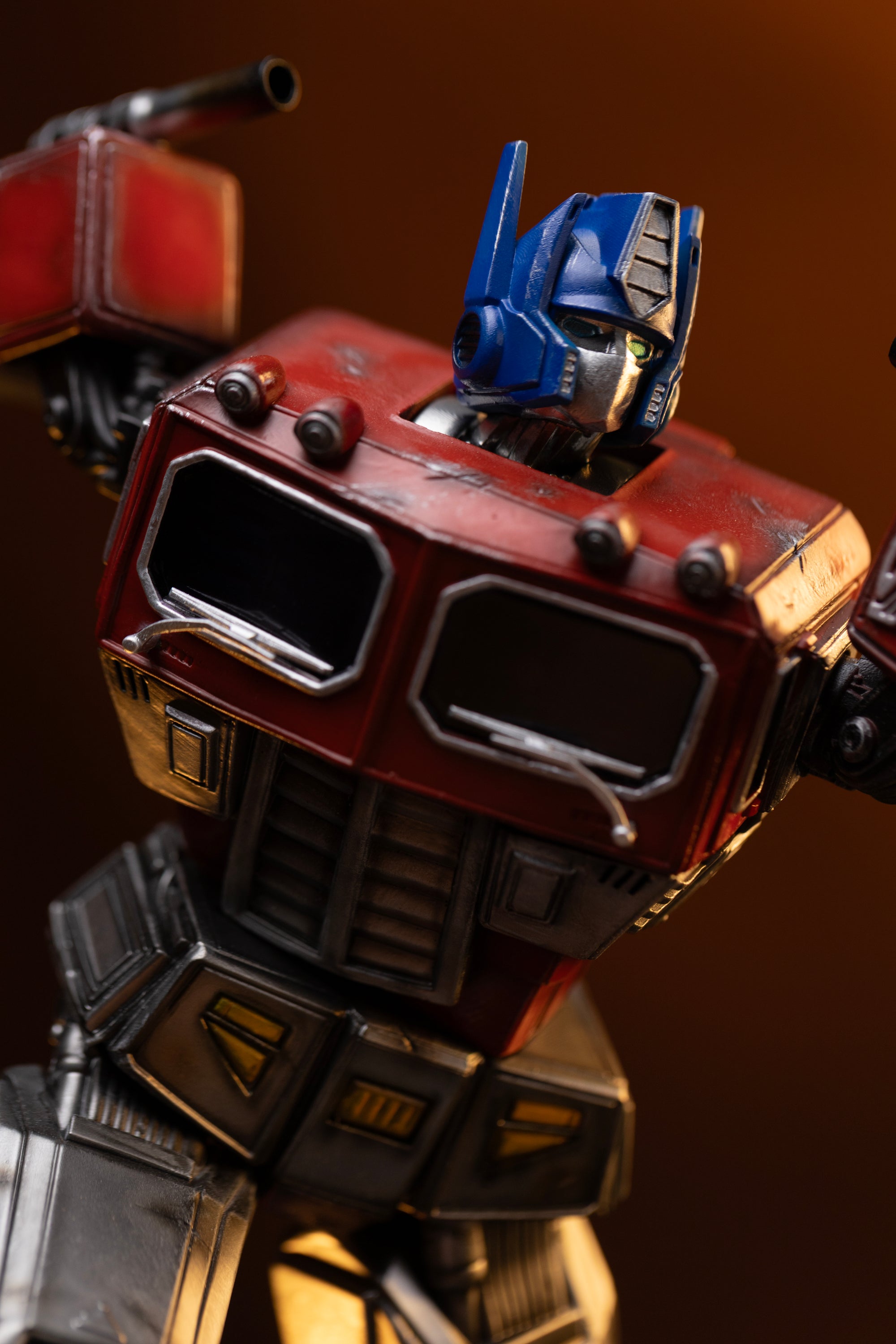 Angled close-up of Optimus Prime's head sculpt and battle-worn red cab chest with silver windshield wipers.