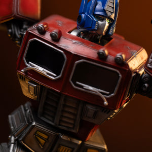 Angled close-up of Optimus Prime's head sculpt and battle-worn red cab chest with silver windshield wipers.