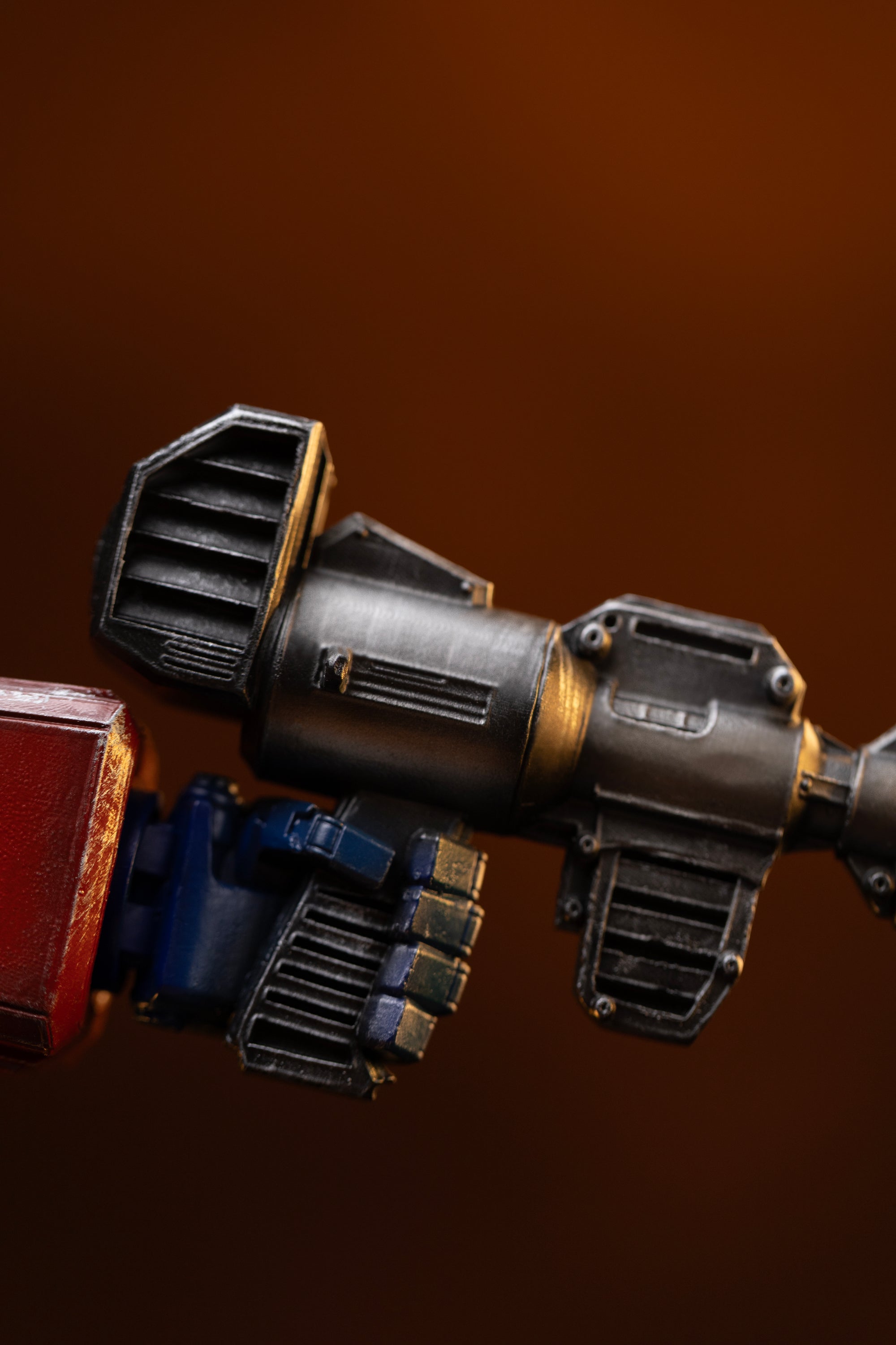 Close-up of the weathered black Ion Blaster rifle gripped in Optimus Prime's hand on the Iron Studios statue.
