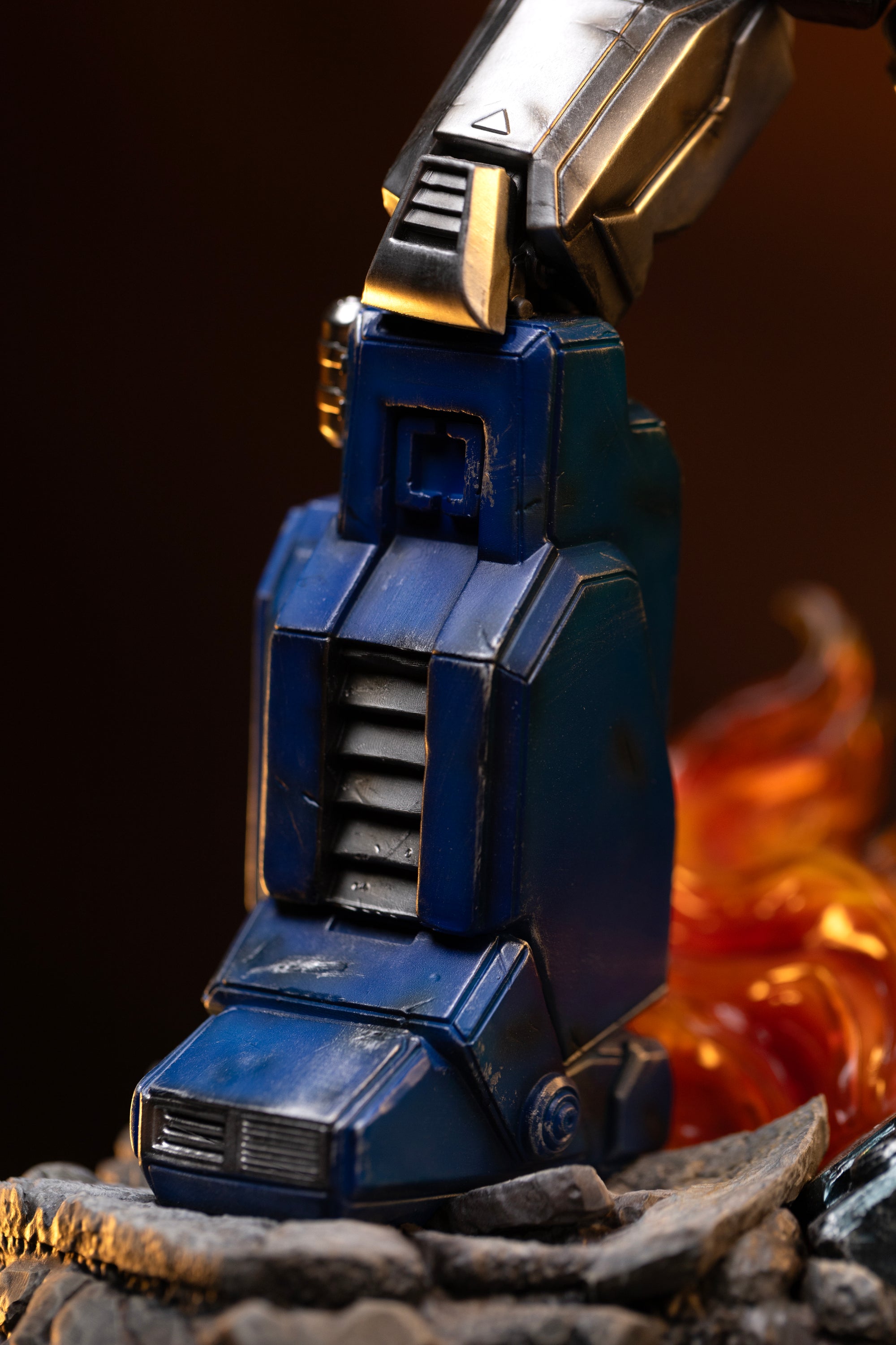 Detailed close-up of the weathered blue leg armor, foot hydraulics, and rubble base of the Optimus Prime Iron Studios statue.