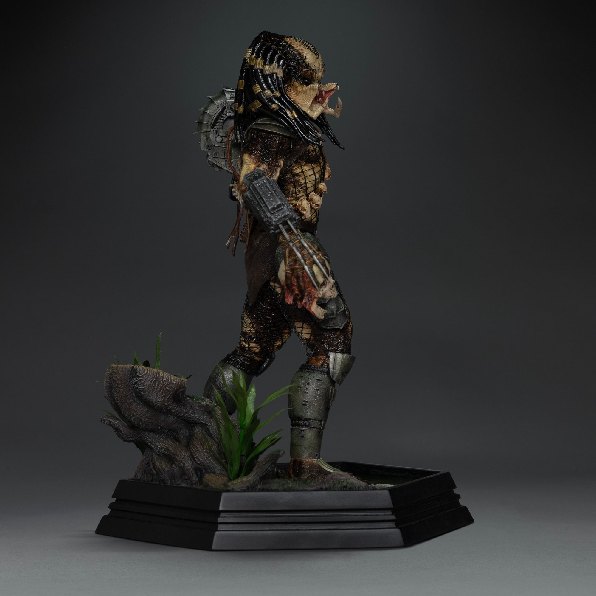 Side view of Iron Studios 1/10 Predator Jungle Hunter unmasked statue holding human skull trophy