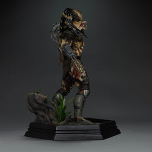 Side view of Iron Studios 1/10 Predator Jungle Hunter unmasked statue holding human skull trophy