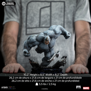 A size comparison photo of the Iron Studios Rhino 1/10 Scale Statue flanked by hands, with its dimensions of 10.2-inch height, 8.5-inch width and 8.2-inch depth listed.