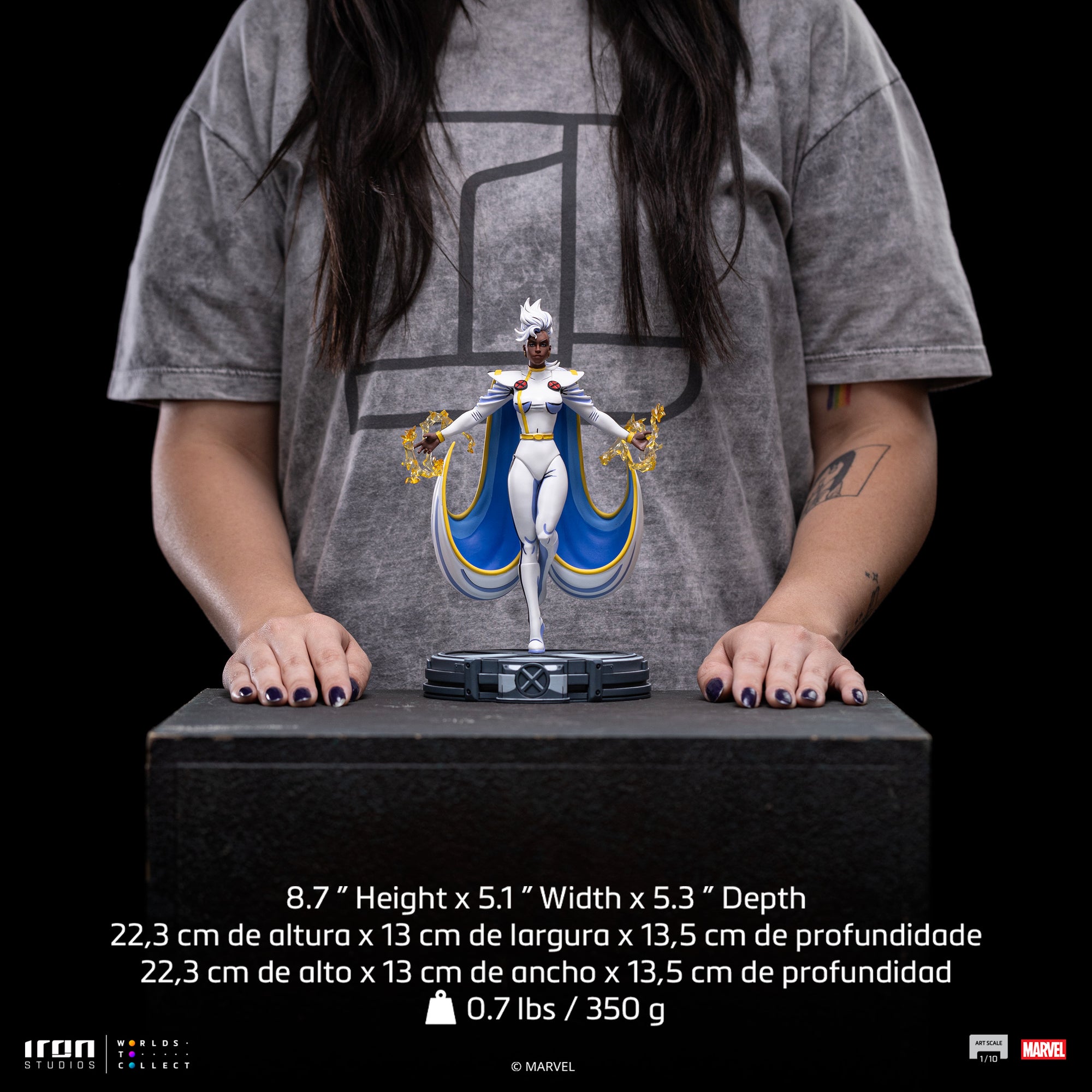 A size comparison photo of the Iron Studios Storm 1/10 Scale Statue held by hands, with its 8.7-inch height and dimensions listed.