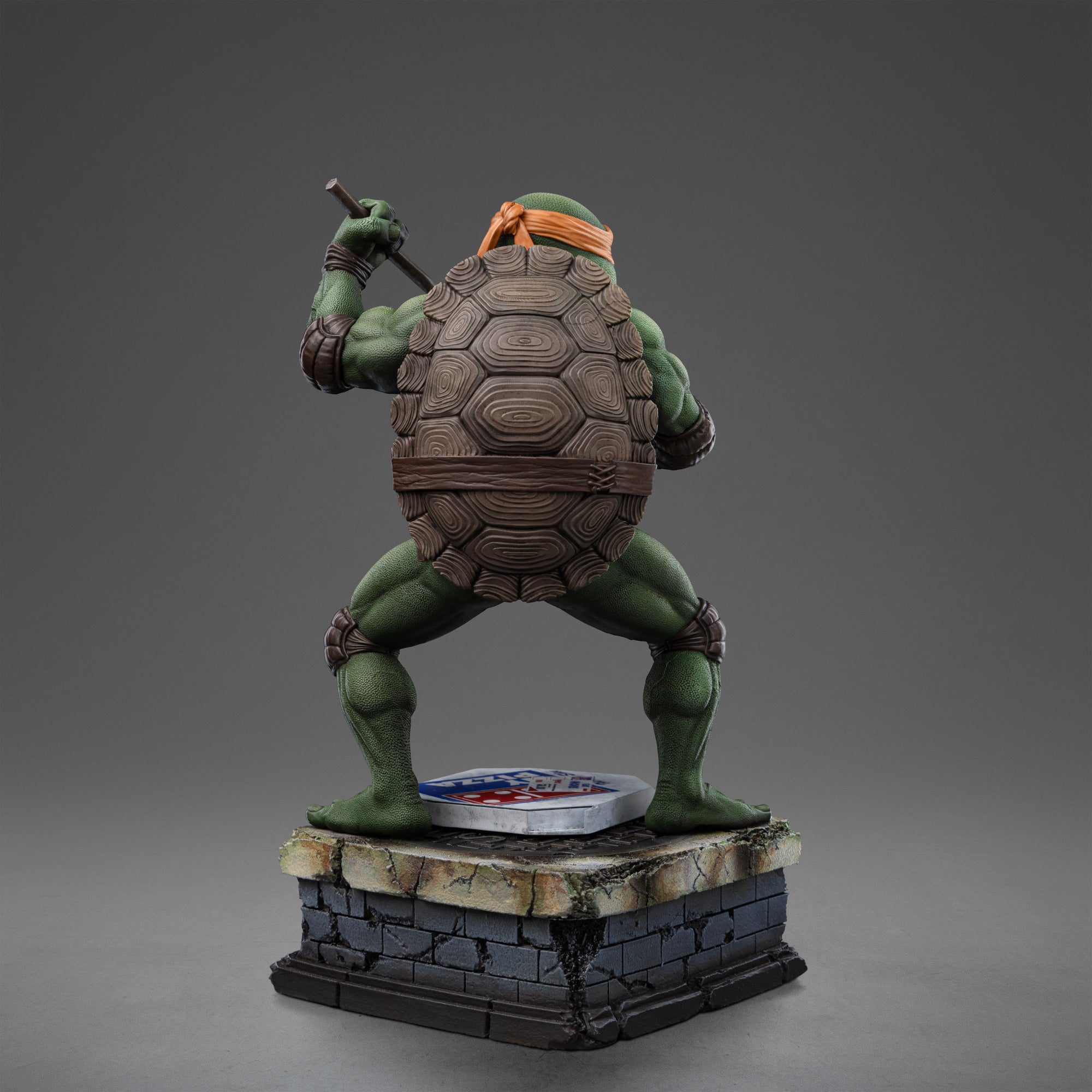 Full rear view of the Iron Studios TMNT 1990 Michelangelo 1/10 scale polystone statue on a sewer diorama base.