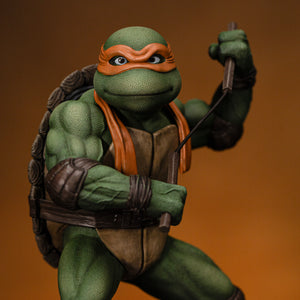 Upper body front close-up of Michelangelo wielding dual nunchaku in a ready combat stance on the Iron Studios 1/10 figure.